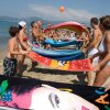 Persone al mare che giocano con asciugamani colorati.