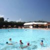 Piscina con persone che nuotano e ombrelloni arancioni sullo sfondo.