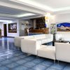 Hall di un hotel con divani bianchi e reception sullo sfondo.