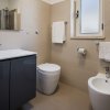Un bagno moderno con lavabo, wc, bidet e asciugamani bianchi su pareti beige.