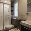 Bagno con doccia, WC, bidet e lavandino sotto una finestra.