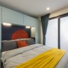 Una camera con letto matrimoniale, coperta gialla, cuscino arancione e armadietti blu chiaro sopra.