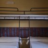Camera con due letti singoli e un letto a castello in metallo nero.