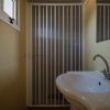 Un bagno con lavabo bianco, rubinetto curvo e doccia con porta a soffietto.