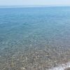 Spiaggia con acqua limpida e ciottoli.