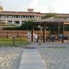 Hotel sullo sfondo con gazebo sulla sabbia in primo piano.