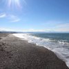 Spiaggia sabbiosa con onde leggere e sole splendente.