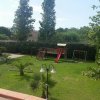 Giardino con prato, giochi per bambini e alberi.