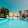 Piscina all'aperto circondata da sedie a sdraio e palme.
