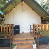 Tenda glamping con veranda in legno e sedie.