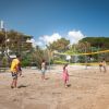 Persone giocano a beach volley su una spiaggia soleggiata.