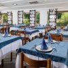 Ristorante con tavoli apparecchiati, tovaglie blu e finestre ampie.