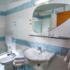 Bagno con piastrelle azzurre, lavabo, bidet e specchio grande.