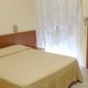 Camera da letto con letto matrimoniale coperto da copriletto beige e tende bianche.