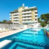 Piscina davanti a un hotel con lettini e giardino colorato.
