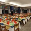 Sala da pranzo elegante con tavoli apparecchiati, tovaglioli rossi e decorazioni alle pareti.