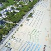 Veduta aerea di una spiaggia attrezzata con ombrelloni e sdraio, vicino a una strada e case.