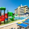 Area piscina con scivoli colorati per bambini e lettini blu sotto ombrelloni.