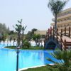 Una piscina all'aperto con un ponte di legno e palme, vicino a un edificio con balconi.