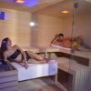 Due persone rilassate in una sauna, un uomo e una donna su lettini di legno.