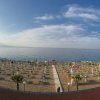 Spiaggia con ombrelloni chiusi e vista sul mare.