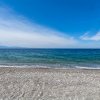 Una spiaggia con ciottoli e un mare blu, sotto un cielo limpido.