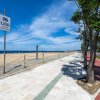 Passeggiata con alberi vicino a una spiaggia e un mare blu; cartello del lido visibile.
