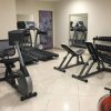 Una palestra con tapis roulant, cyclette, panca pesi e rastrelliera per manubri.