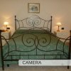 Letto in ferro battuto con lenzuola verdi, due comodini e lampade.