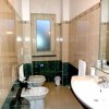 Bagno con piastrelle beige, lavabo, bidet e doccia, piccola finestra.