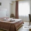 Camera con letto matrimoniale, lenzuola beige, finestra ampia e tende.
