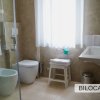 Un bagno moderno con doccia, bidet e finestra con tenda bianca.