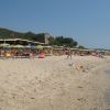 Spiaggia con ombrelloni gialli e blu e torre in lontananza.