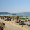 Una spiaggia con ombrelloni gialli e verdi, lettini e mare calmo in lontananza.
