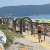 Un ingresso con archi su una spiaggia con ombrelloni gialli e verdi, un uomo cammina su un sentiero.