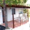 Una casa con portico in legno, due sedie bianche e un tavolo all'aperto.
