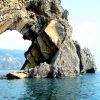 Una formazione rocciosa con un grande arco sopra il mare.