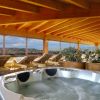 Vasca idromassaggio e lettini in una veranda panoramica.