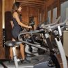 Donna su cyclette in una palestra con pareti in legno.