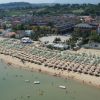 Spiaggia affollata con ombrelloni e complessi residenziali vicini.