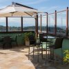 Terrazza con sedie, tavoli e ombrellone, vista collinare.