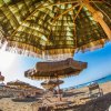 Ombrelloni di paglia e lettini su una spiaggia assolata.