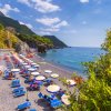 Spiaggia sabbiosa, ombrelloni variopinti e mare azzurro.