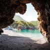 Vista da grotta su spiaggia con mare limpido.