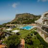Resort con piscina e vista su collina verde.