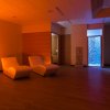 Sala relax con luce soffusa e poltrone bianche.