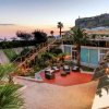 Giardino con zona lounge e vista mare al tramonto.