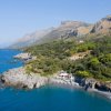 Costa rocciosa con vegetazione e mare blu.
