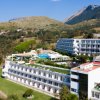 Grande hotel bianco vicino a montagne e vegetazione.