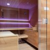 Sauna in legno con luce soffusa viola.